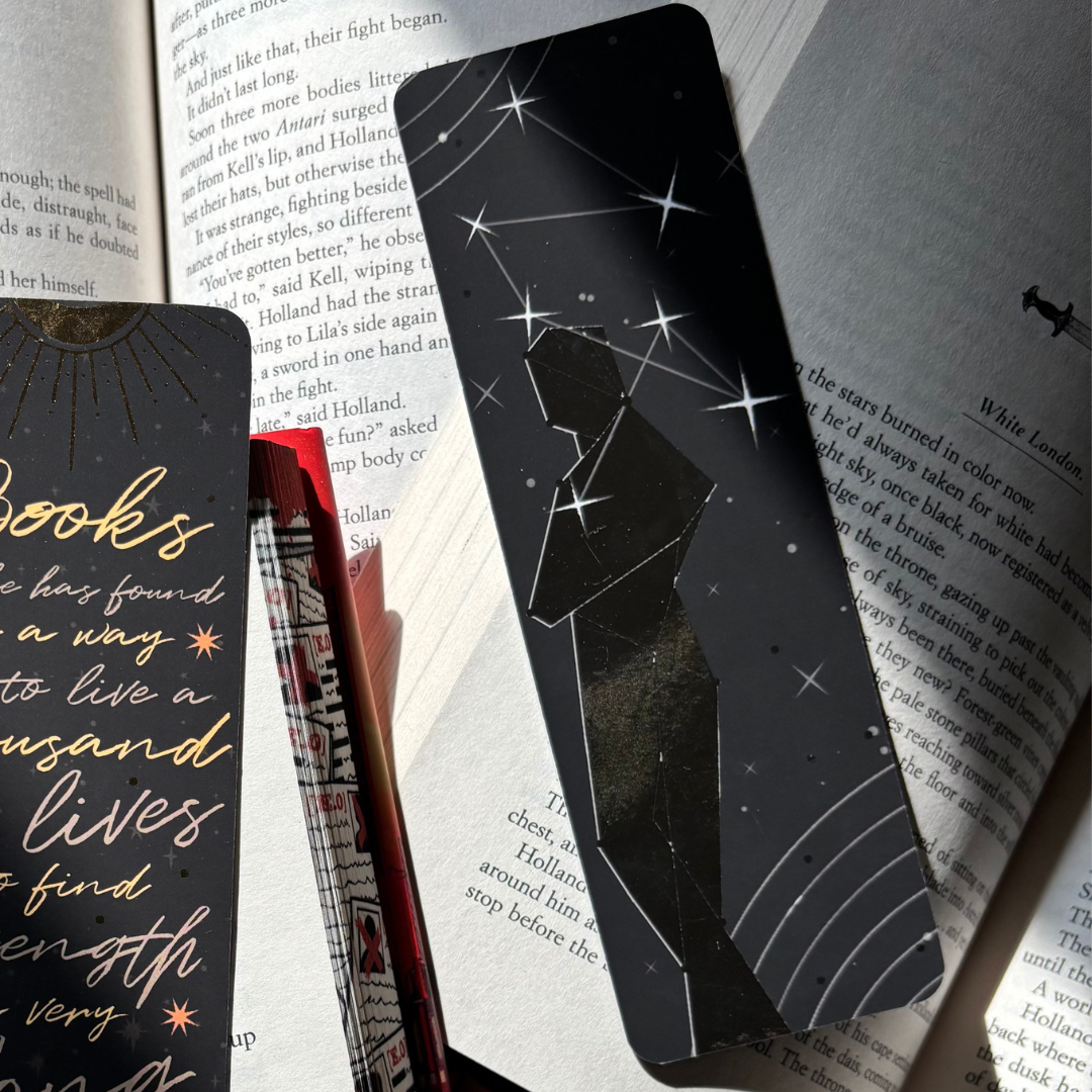 Black bookmark with stars and a foiled silhouette, pictured against a background of open books