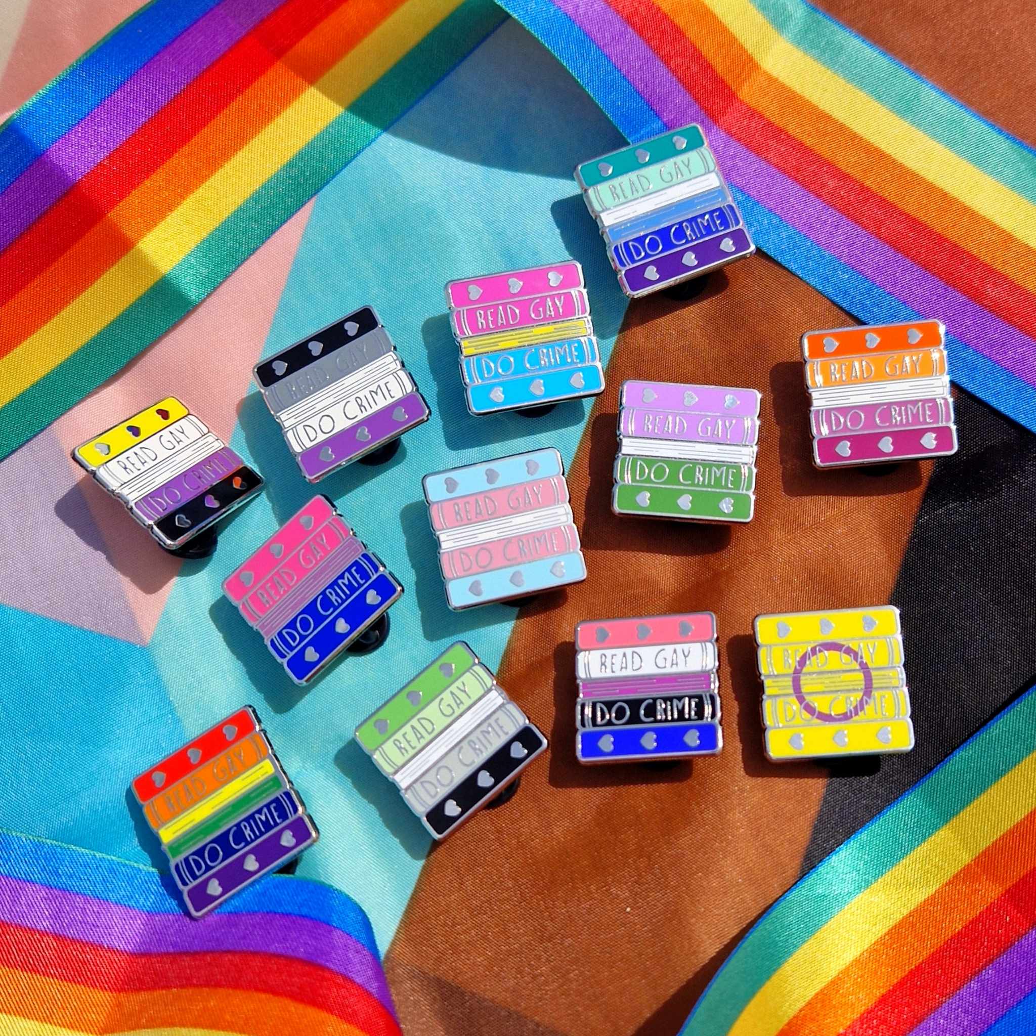 The Read Gay Do Crime Pride Pin Collection resting against the pride flag.