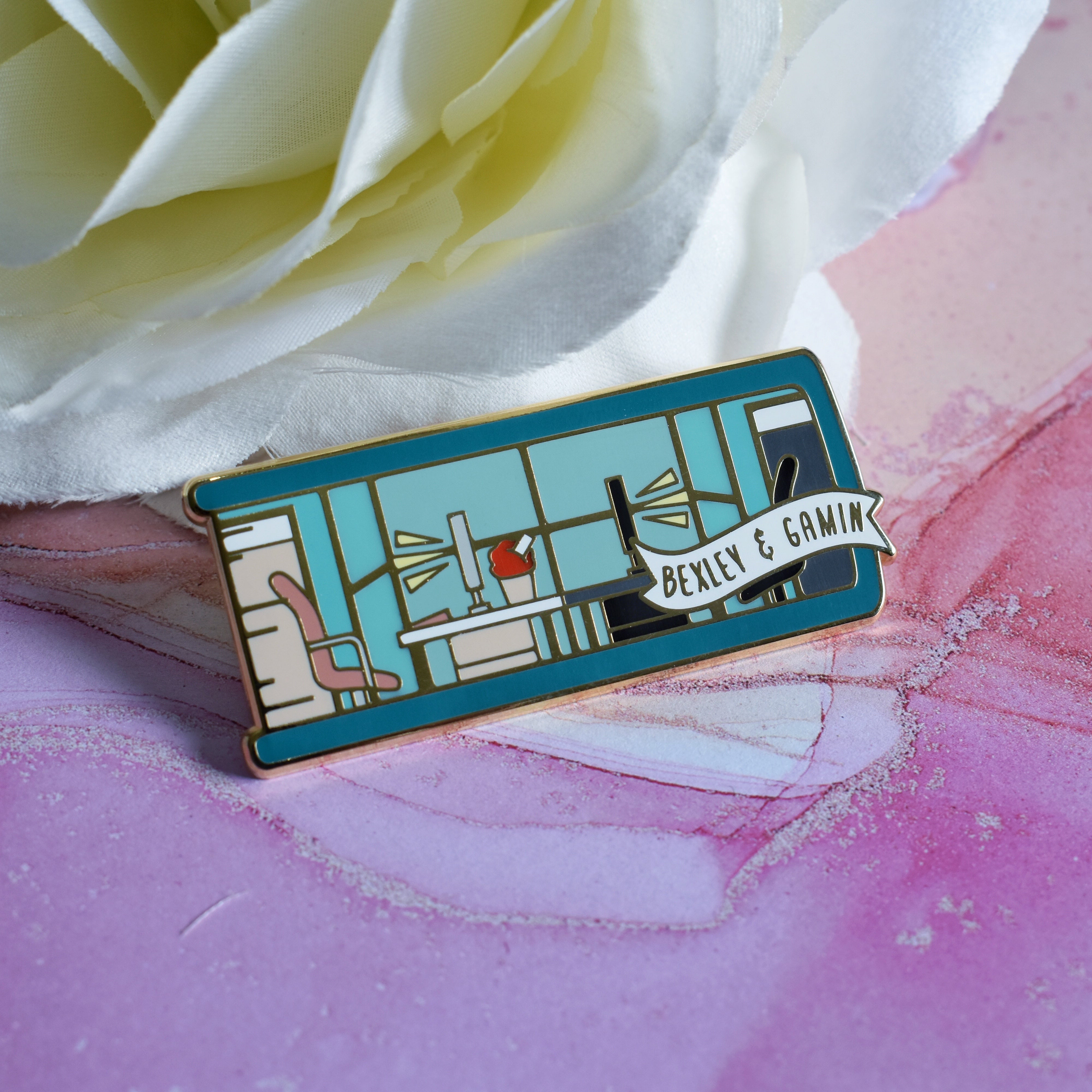 The Hating Game inspired enamel pin featuring Bexley and Gamin's office area.