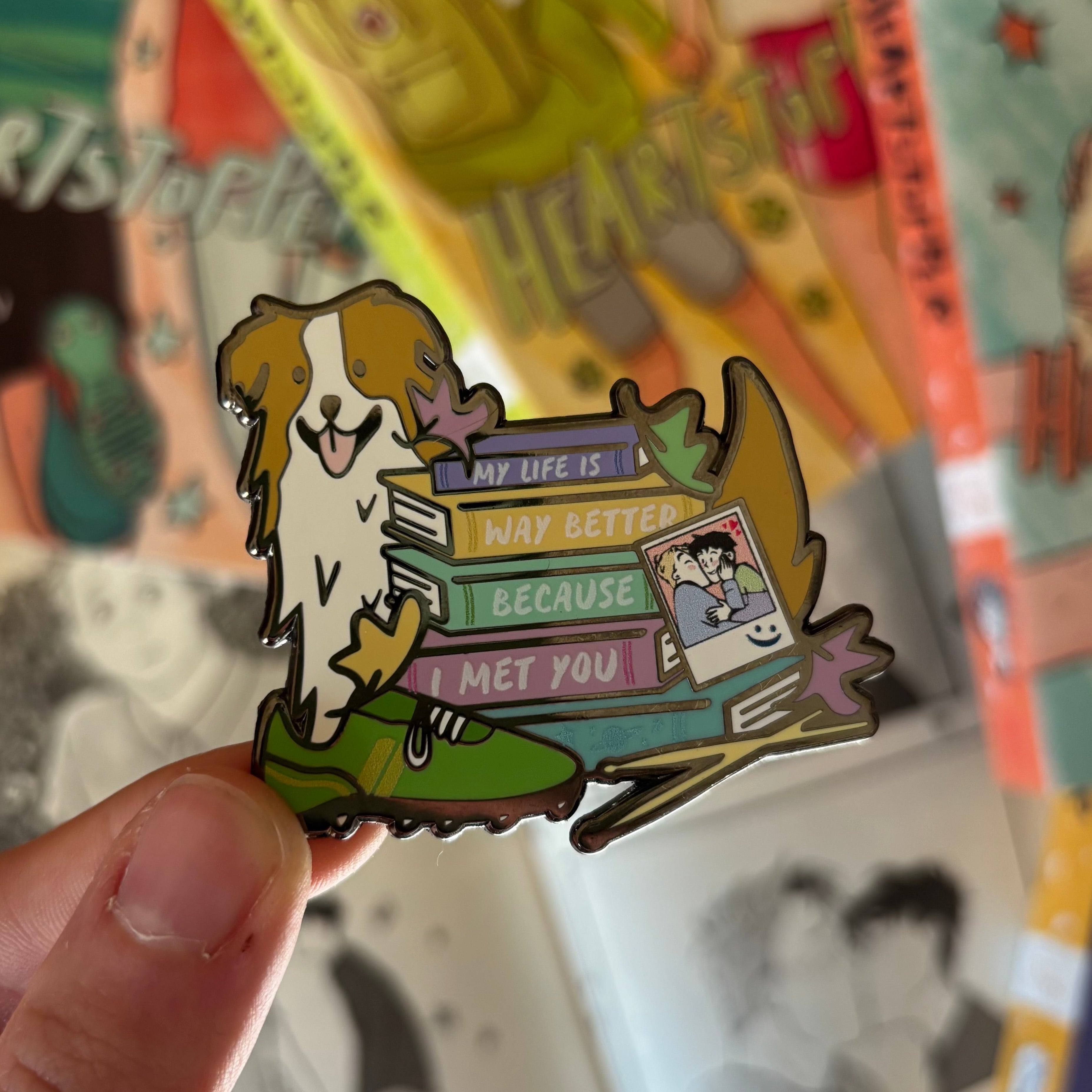 Story stack enamel pin inspired by Heartstopper by Alice Oseman, pictured against the Heartstopper graphic novels.