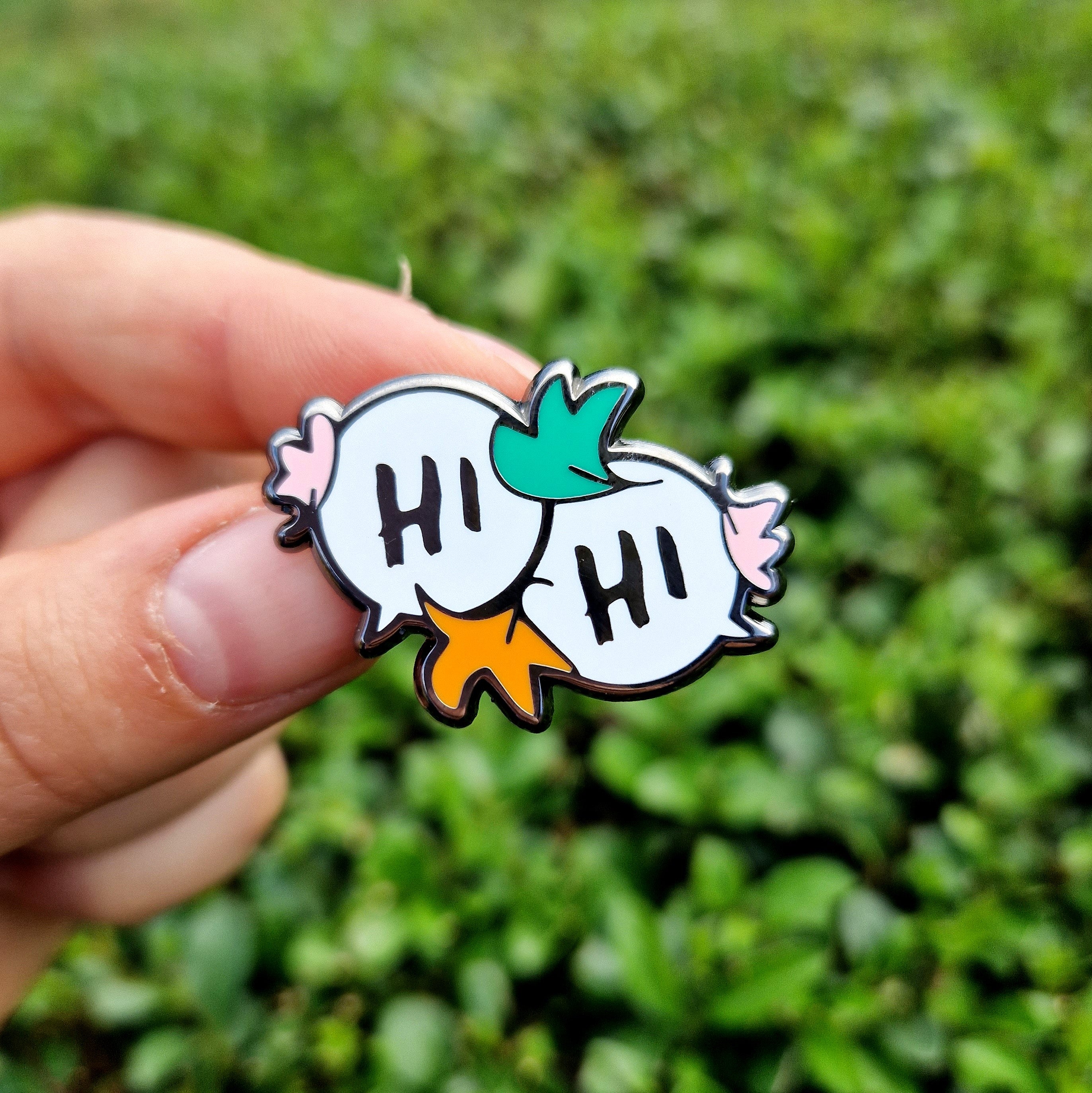 Enamel pin of two speech bubbles with the text "Hi", inspired by Alice Oseman's Heartstopper graphic novels.