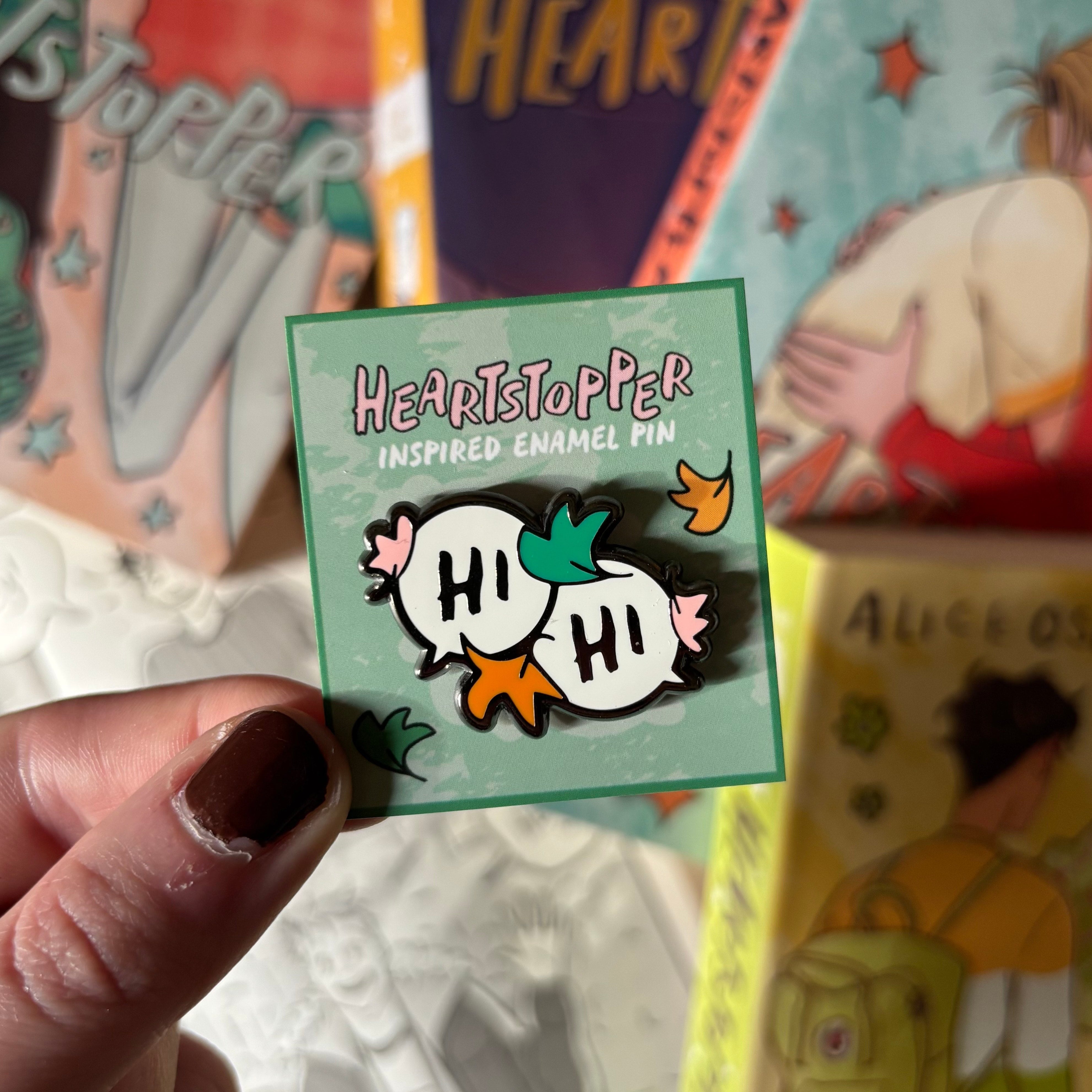 Enamel pin of two speech bubbles with the text "Hi", inspired by Alice Oseman's Heartstopper graphic novels.