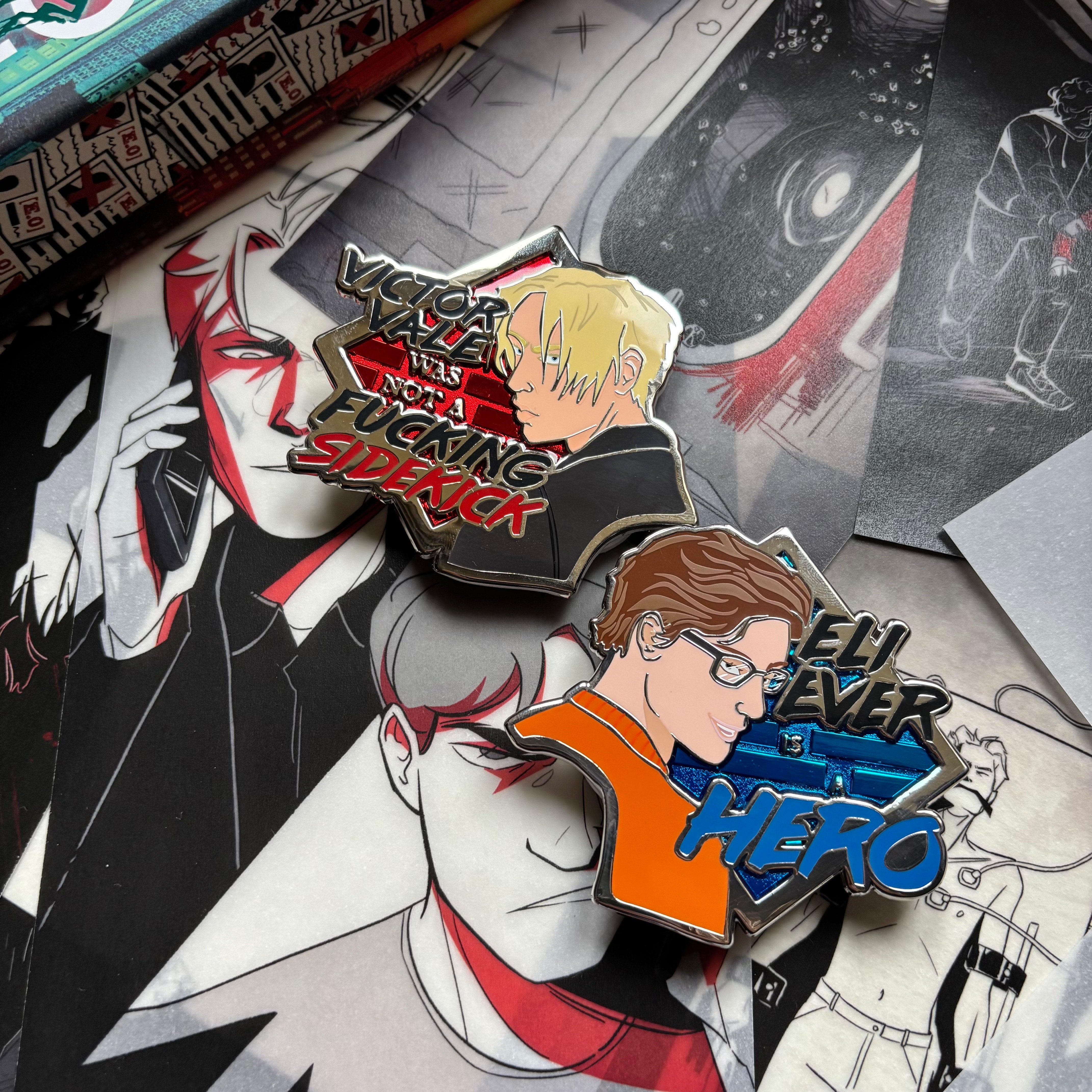LitPins&Co Vicious Deluxe Enamel Pins resting against the page overlays. The pins feature Victor Vale and Eli Ever along with their quotes: "Victor Vale was not a f**king sidekick" and "Eli Ever is a Hero"