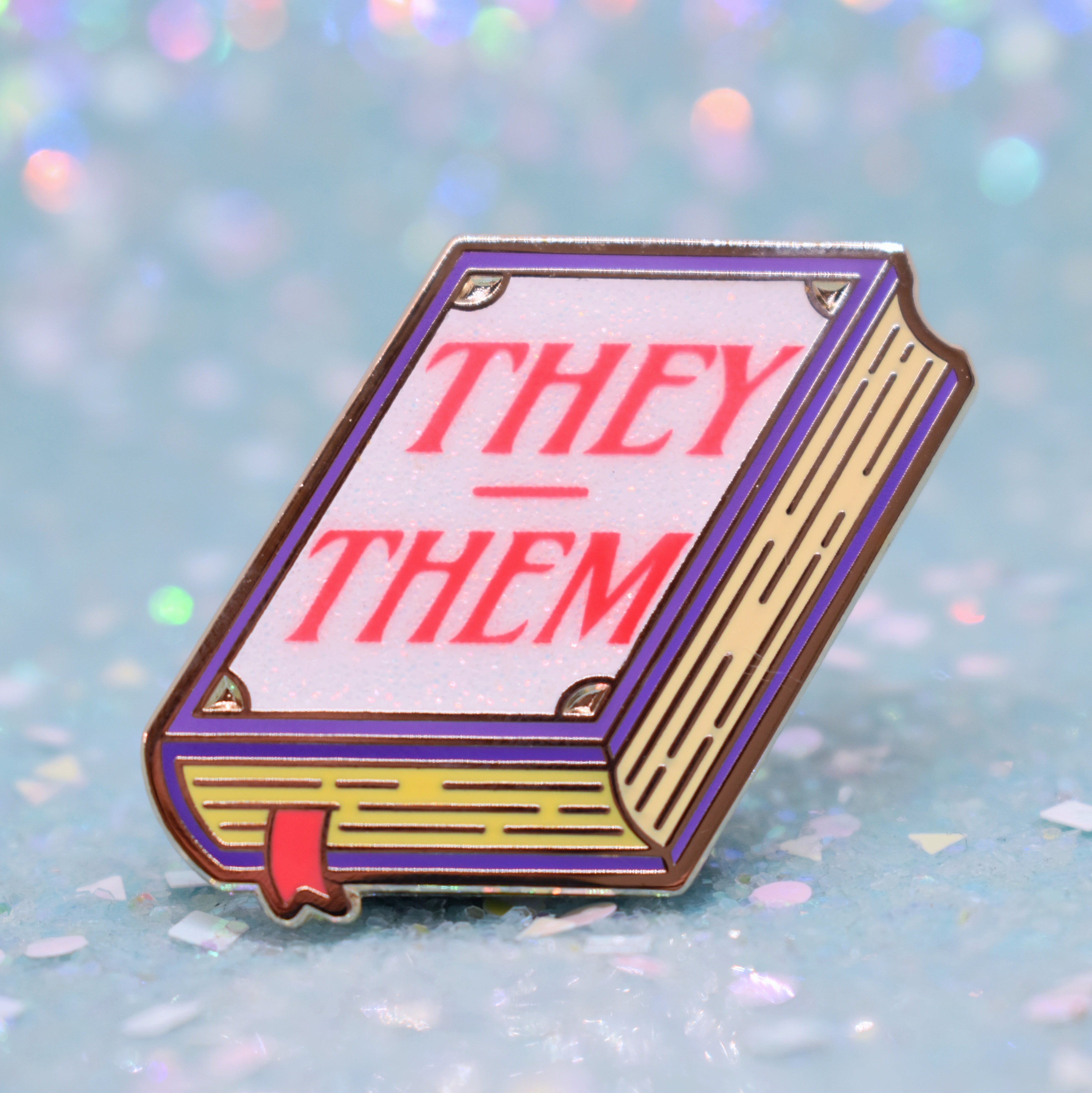 Book shaped pronoun pin on a decorative background