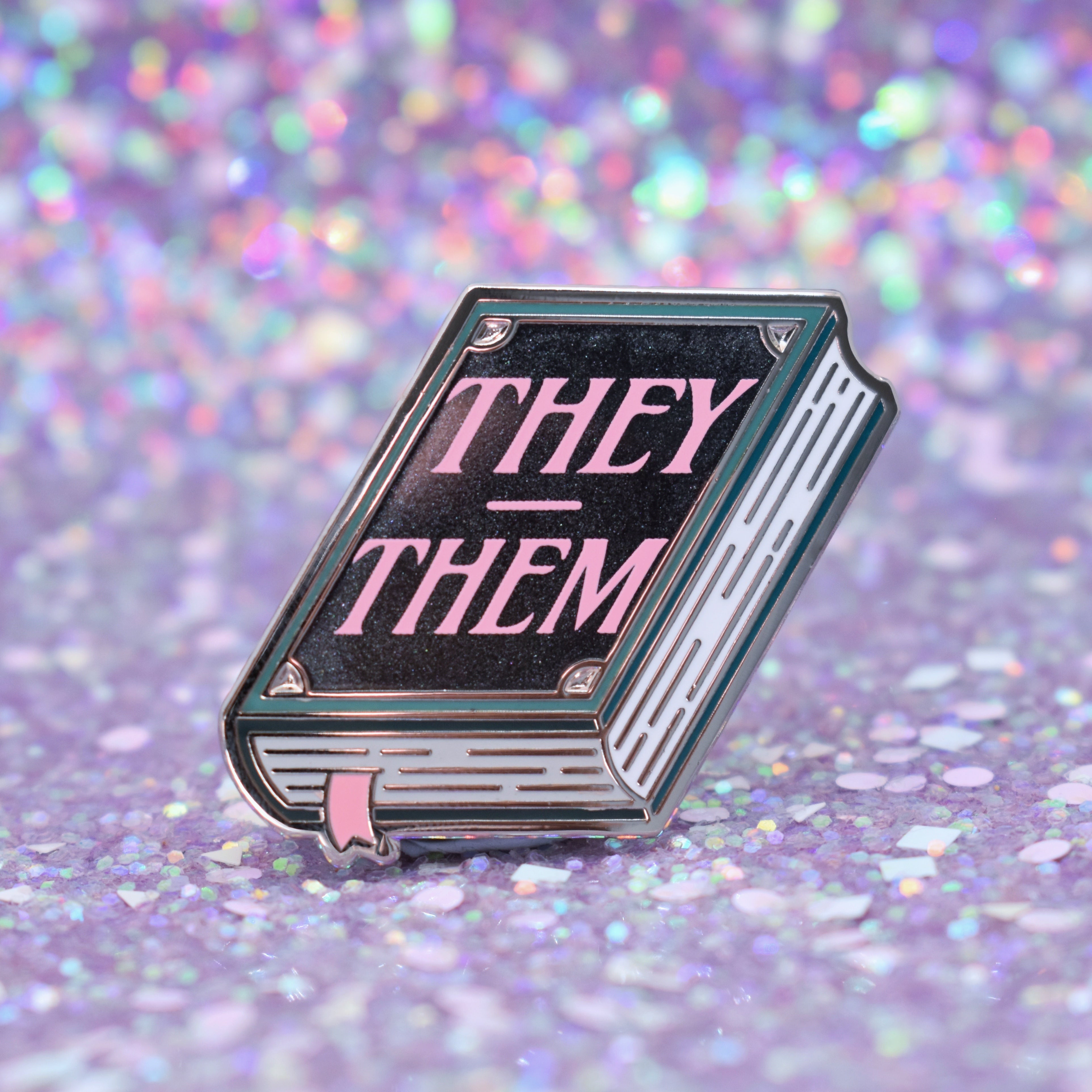 Book shaped pronoun pin on a decorative background
