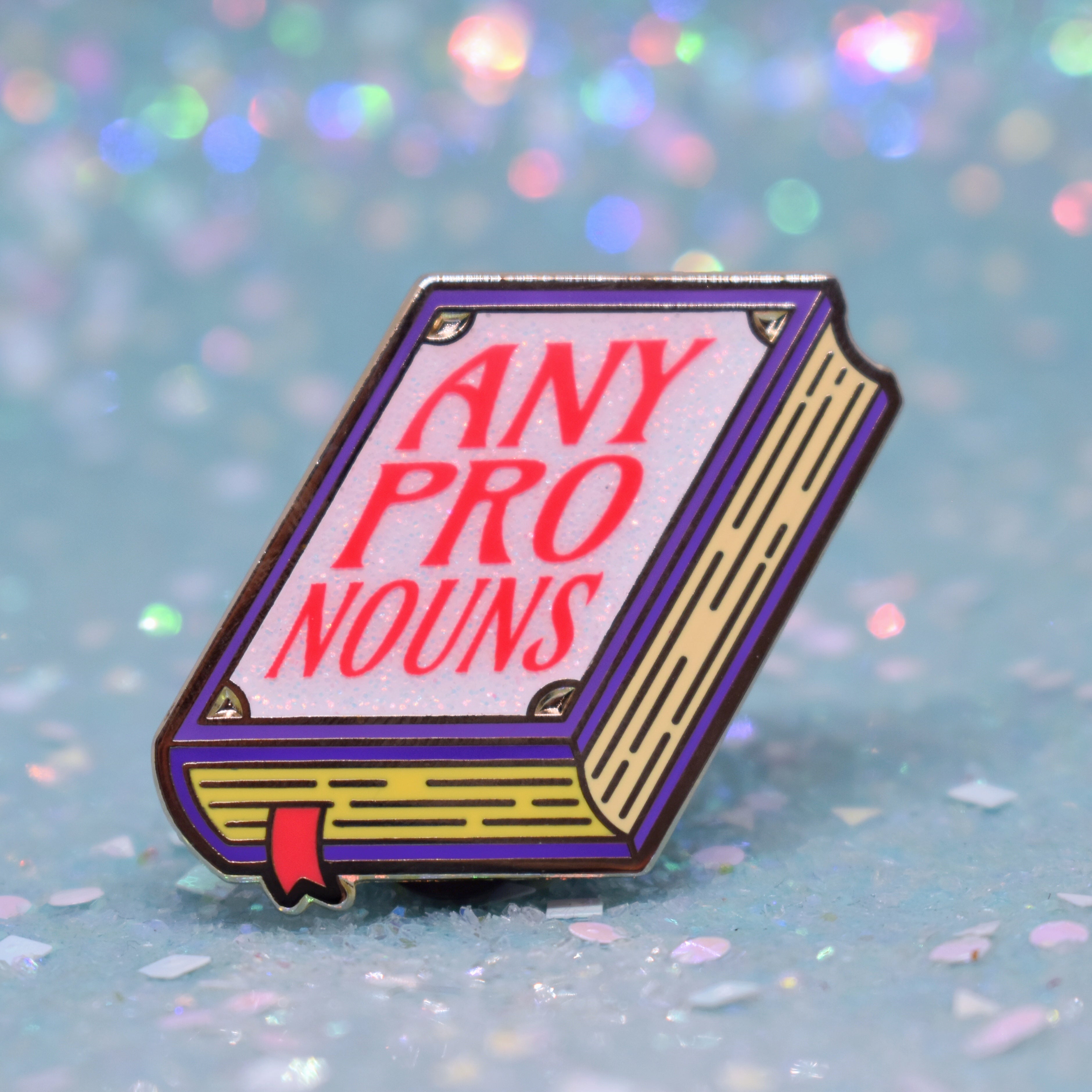 Book shaped pronoun pin on a decorative background