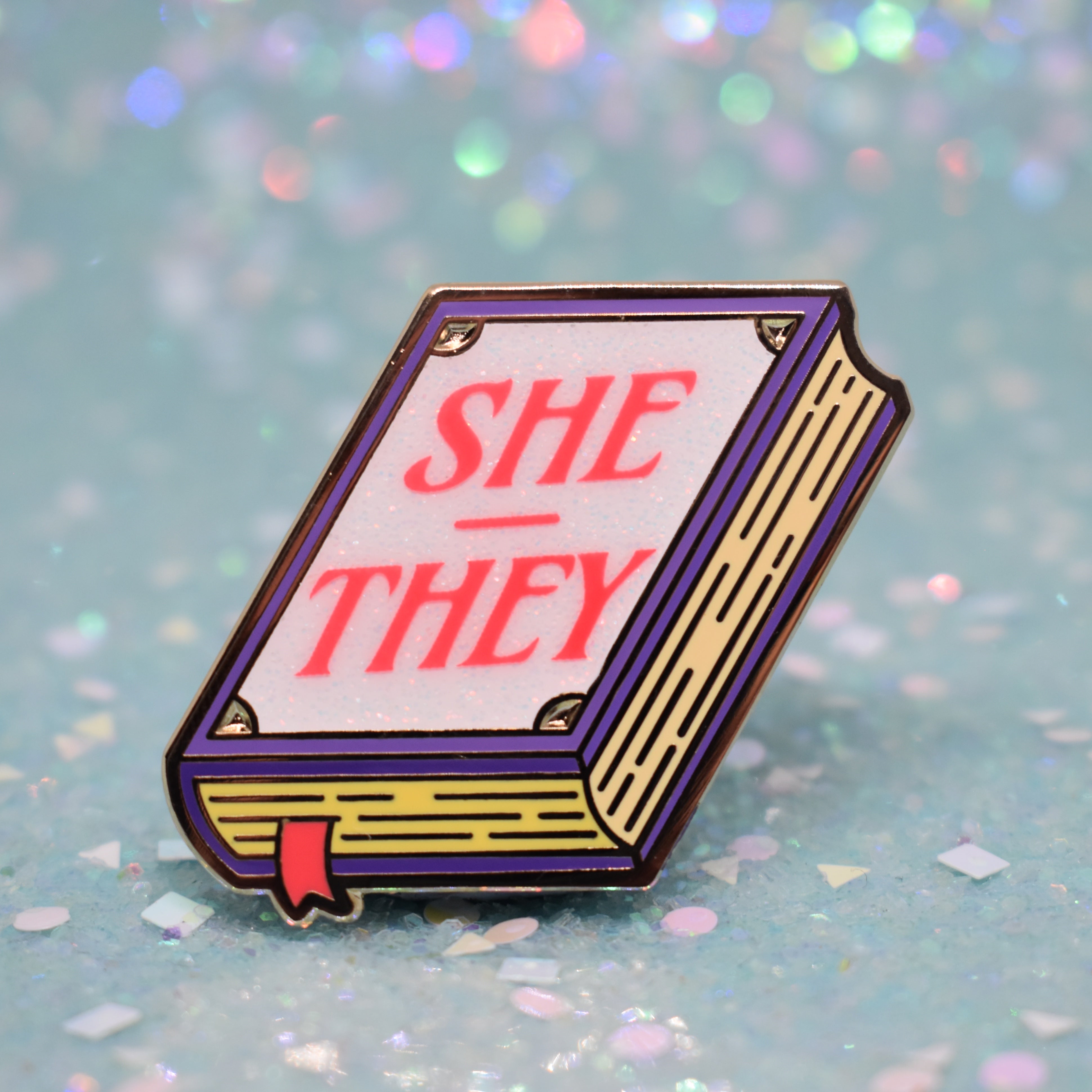 Book shaped pronoun pin on a decorative background
