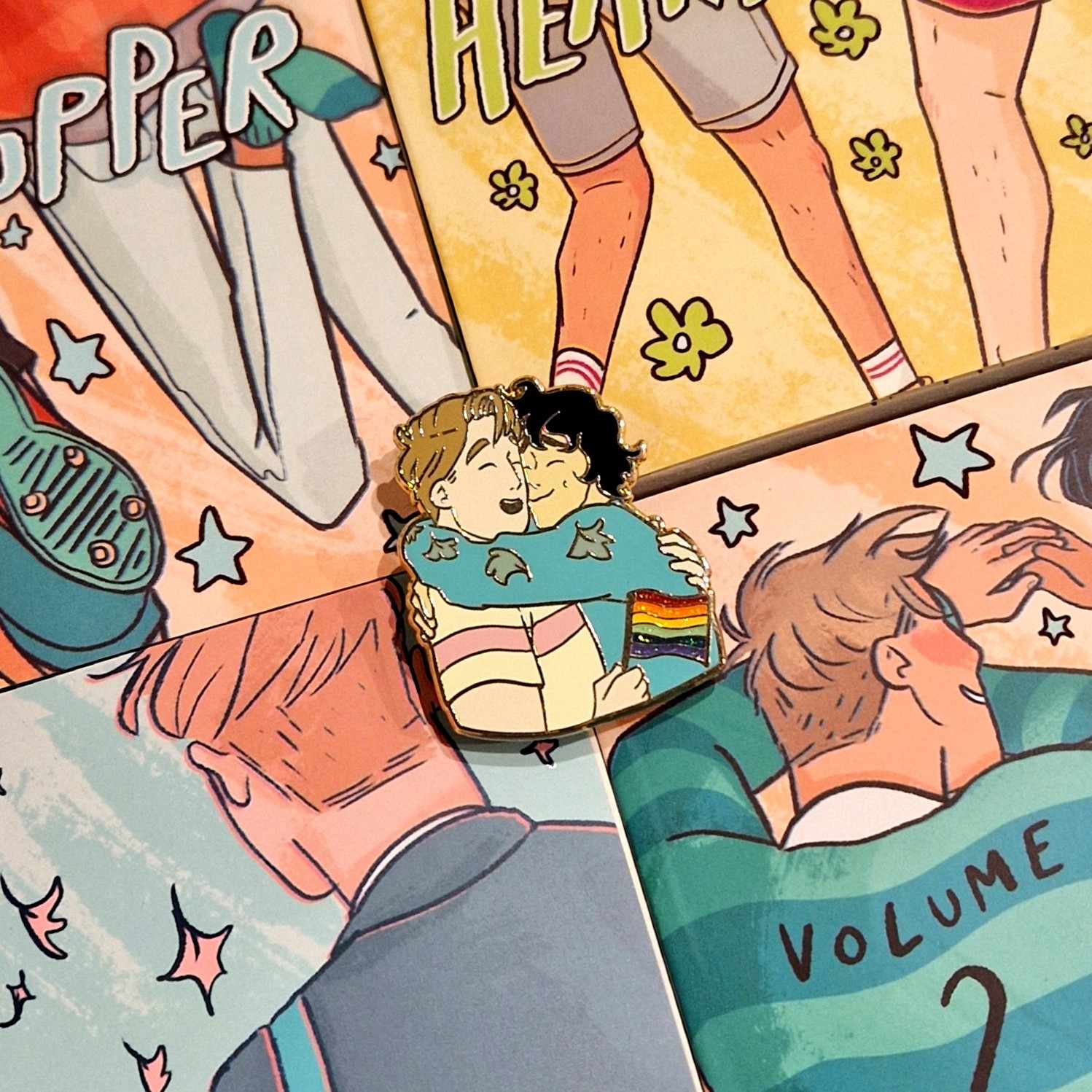 Officially licensed Heartstopper pride pin. Features Nick and Charlie in an embrace with Nick holding a Pride Flag., designed by Alice Oseman.