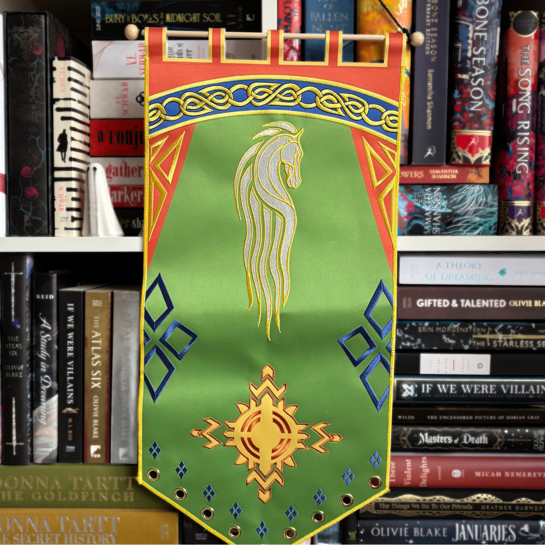 Lord of the Rings inspired pin banner, featuring a horse design and other decorative elements on a green background with red, blue, and yellow details. Pictured against a bookshelf.