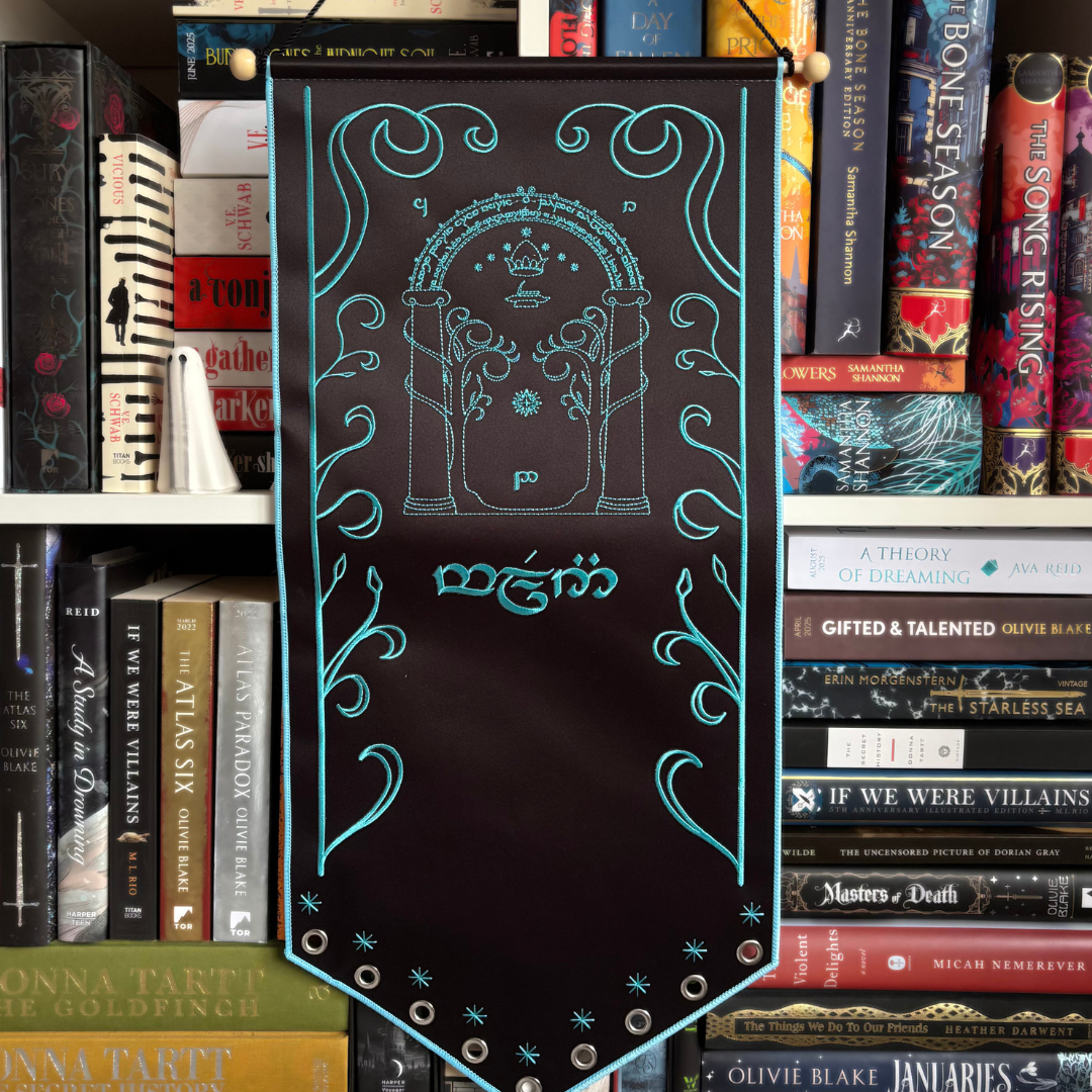 The Speak Friend decorative pi banner with intricate designs and text on a black background. Inspired by Lord of the Rings. Pictured against a bookshelf.