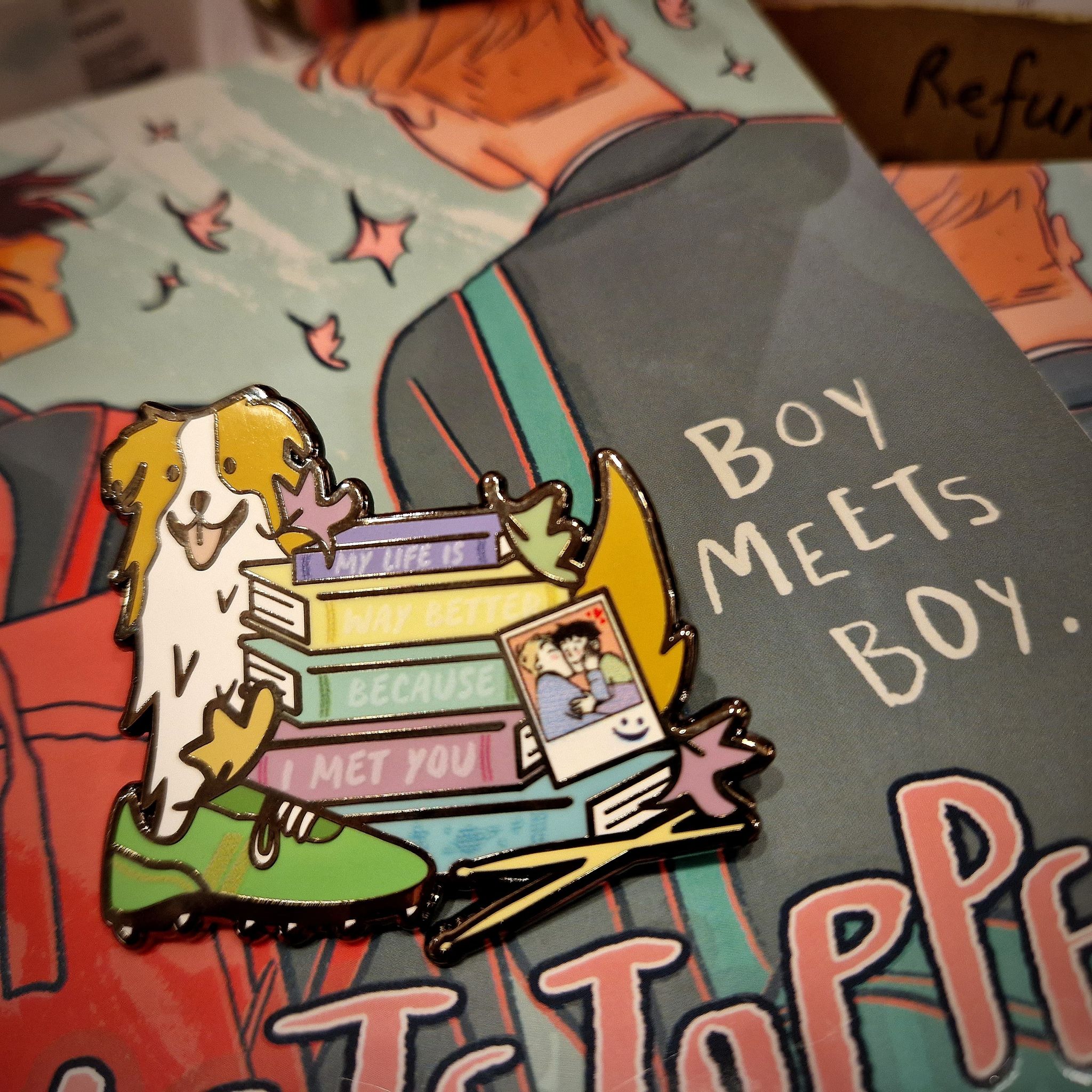 Story stack enamel pin inspired by Heartstopper by Alice Oseman, pictured against the Heartstopper graphic novels.