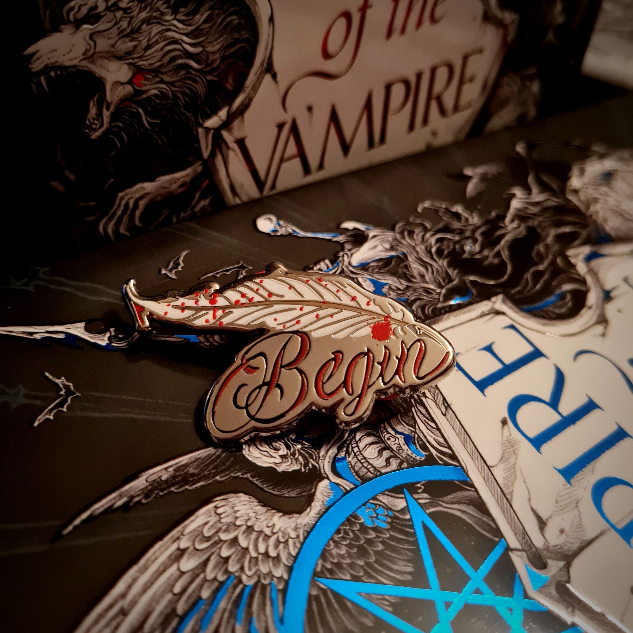 Empire of the Vampire by Jay Kristoff Inspired Pin, a quill with the word Begin written underneath in read.