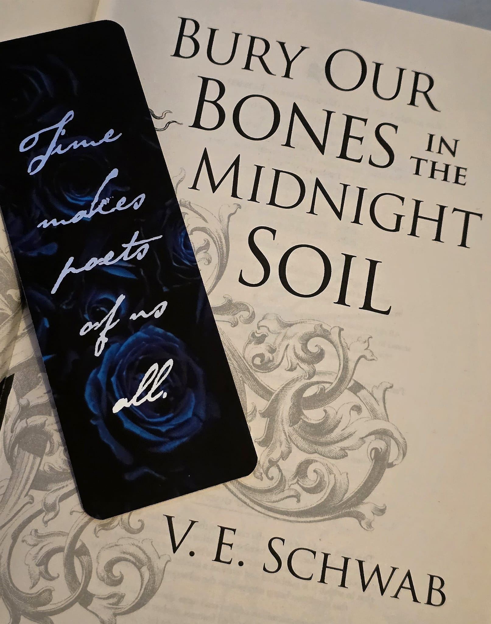 LitPins&Co Bury Our Bones in the Midnight Soil by V.E Schwab inspired bookmark featuring a background of black and blue roses with the quote from the book: "Time Makes Poets of Us All"