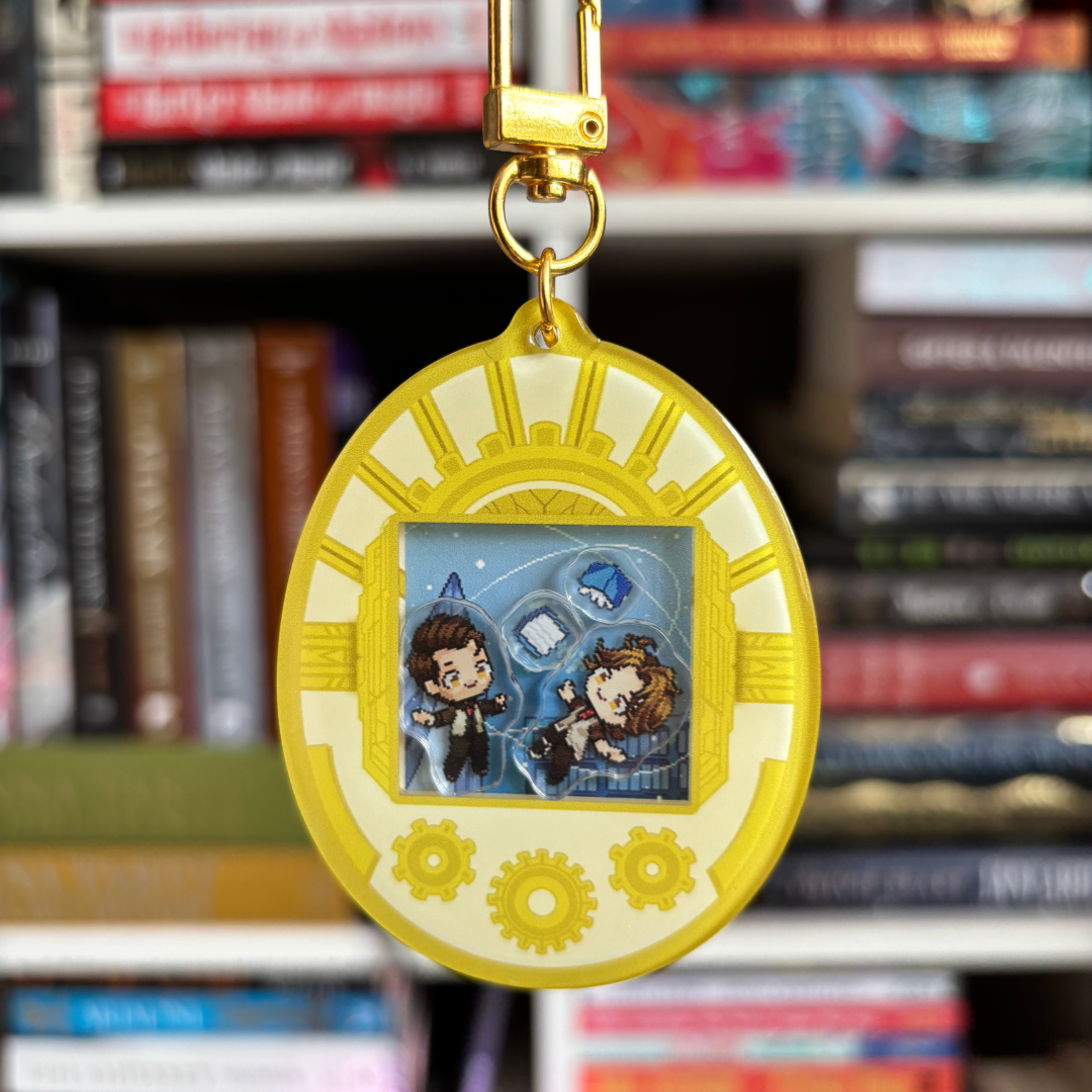 A yellow, white, and gold Tamagotchi style shaker keychain inspired by Arcane, featuring Jayce and Viktor. Held in front of a book shelf.