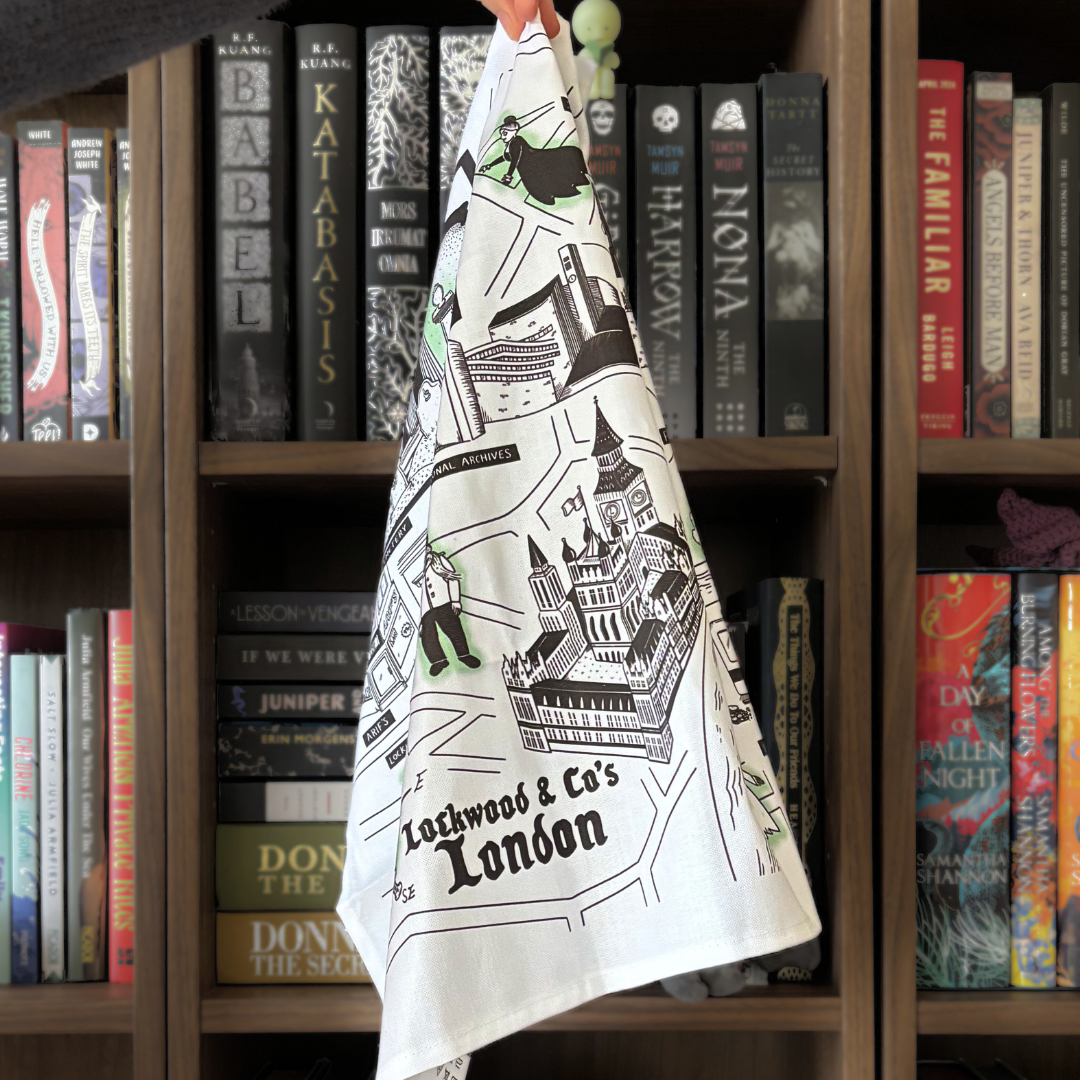 A white tea towel featuring a design of "Lockwood & Co's London," showing landmarks from the series and ghosts.