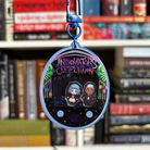 A black and blue Tamagotchi style shaker keychain inspired by Arcane, featuring Powder and Ekko. Held in front of a book shelf.