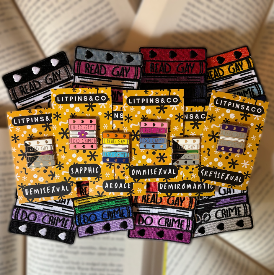 LitPIns&Co Read Gay Do Crime Patches against open books with the newest enamel pins resting on top of them. 