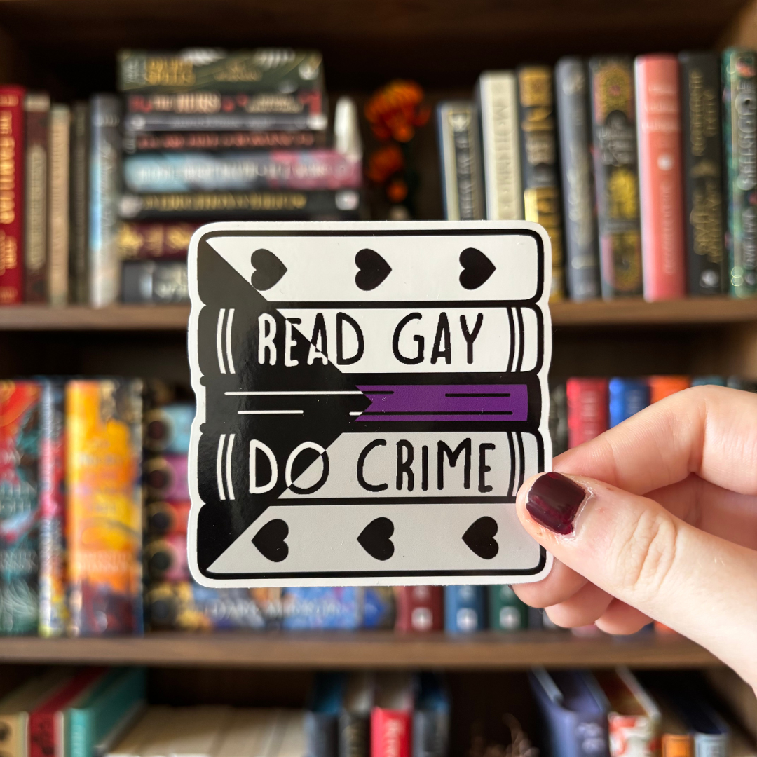 A large sticker designed to look like a stack of books in the colours of the demisexual pride flag, with text reading "Read Gay Do Crime"