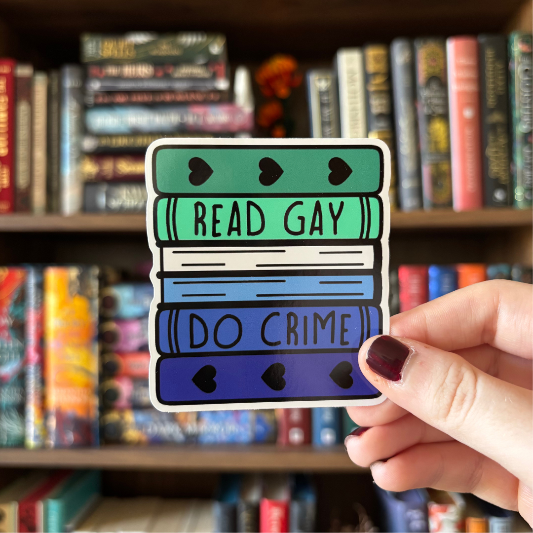 A large sticker designed to look like a stack of books in the colours of the gay pride flag, with text reading "Read Gay Do Crime"