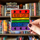 A large sticker designed to look like a stack of books in the colours of the LGBTQ+ pride flag, with text reading "Read Gay Do Crime"
