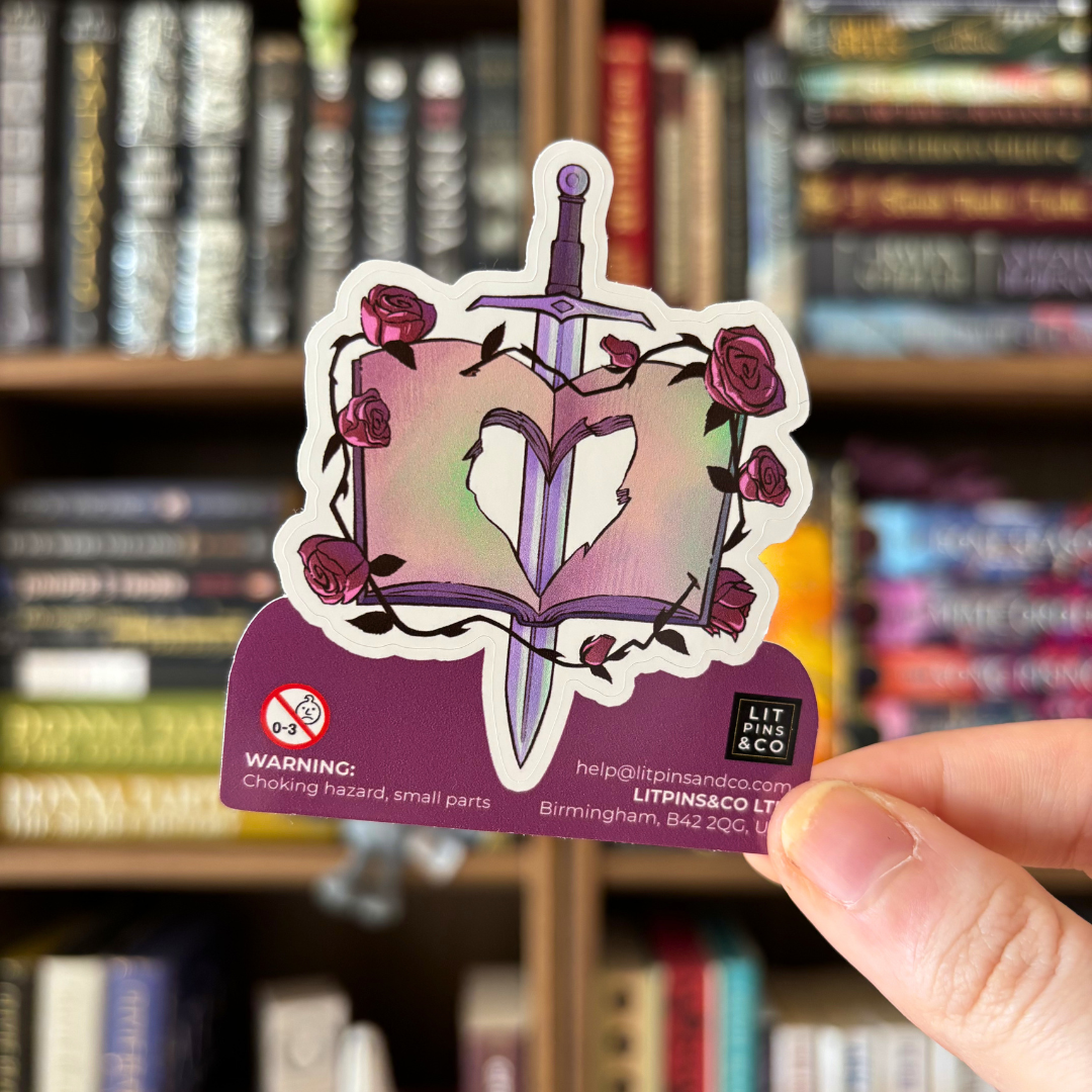 Book shaped sticker inspired by the romantasy genre, featuring an open book with a heart cut-out, a sword, and roses.