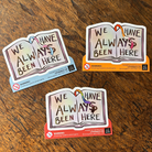 Book-shaped stickers with the text "We have always been here" decorated in colours of various pride flags