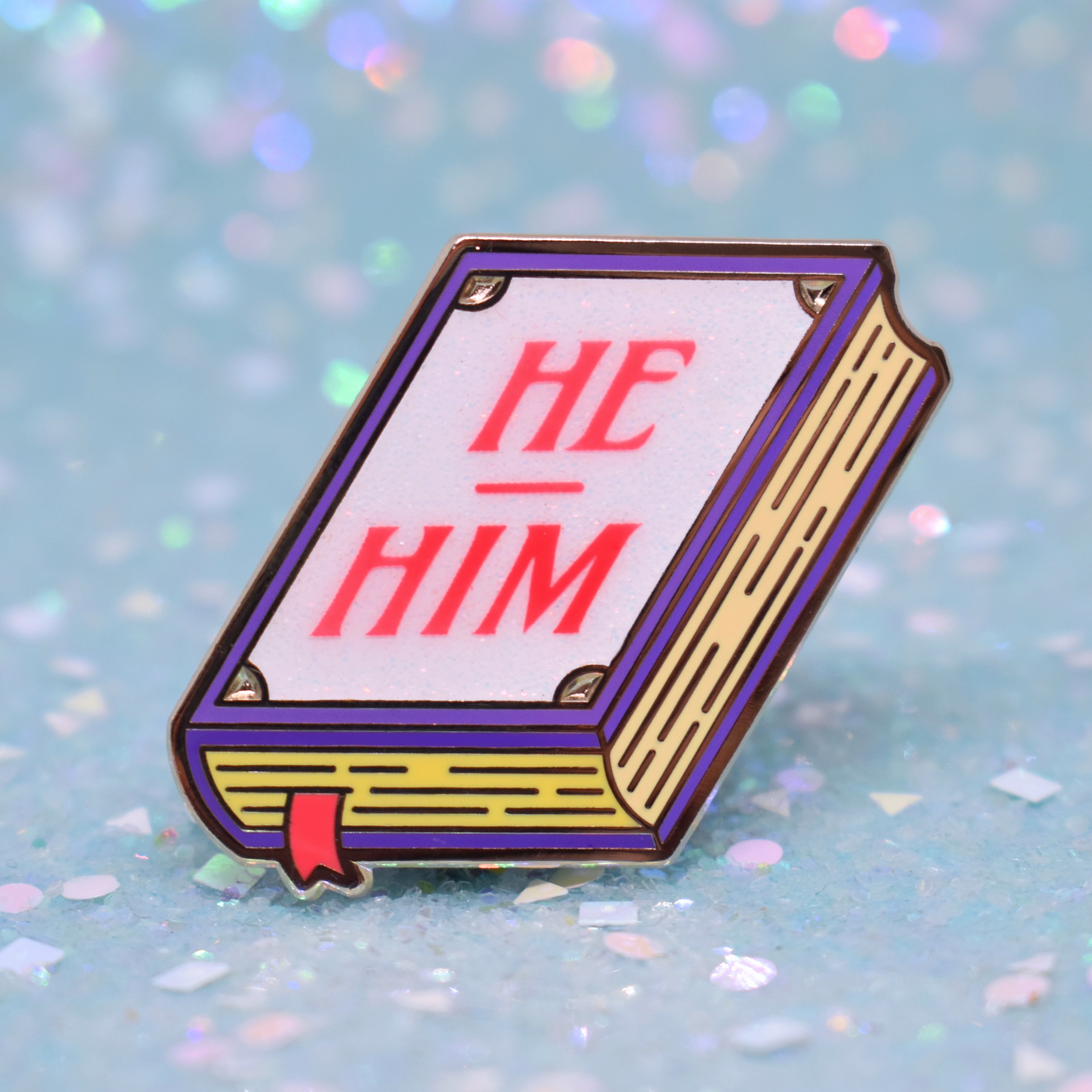 Book shaped pronoun pin on a decorative background 