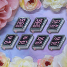 Set of book shaped pronoun pins on a decorative background with flowers