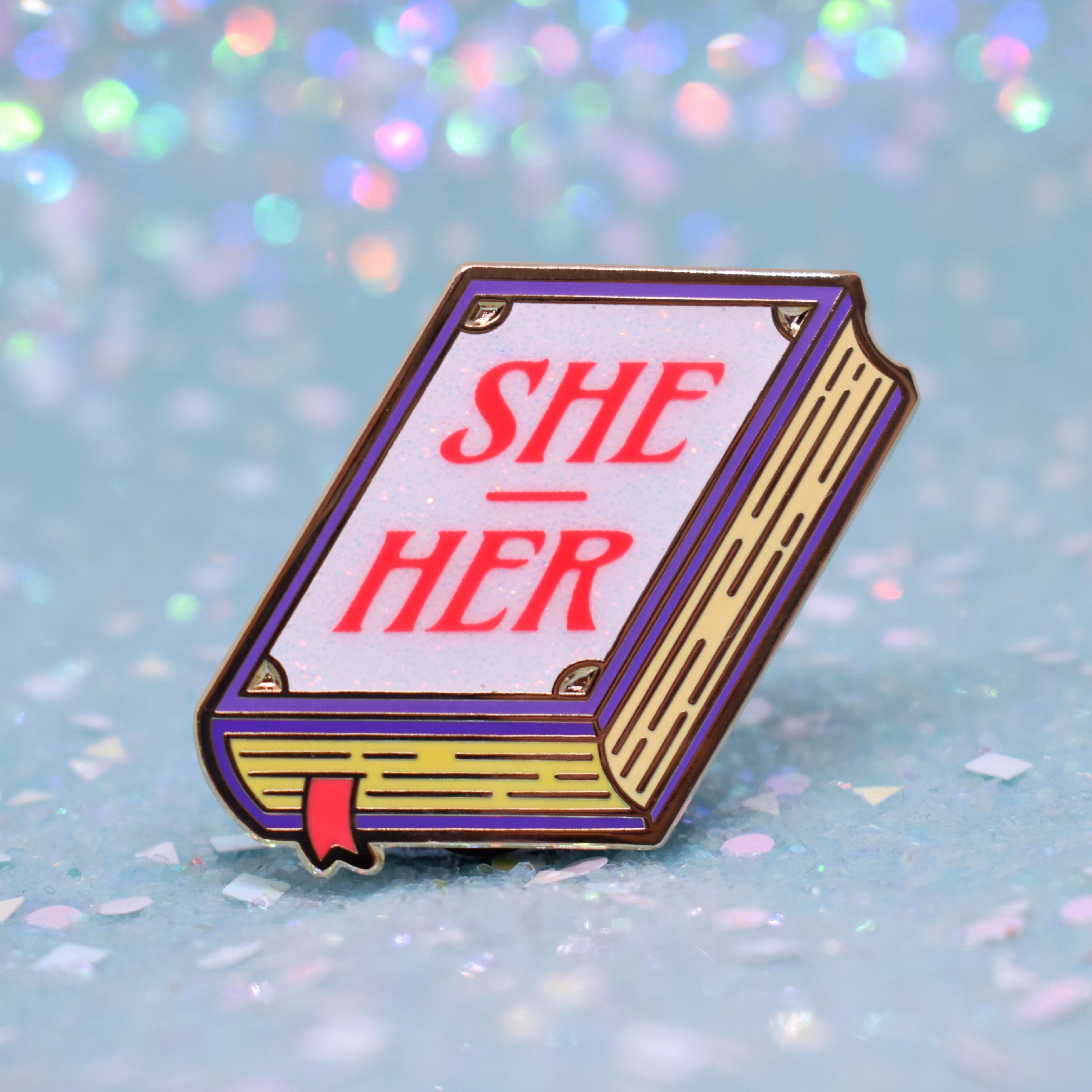 Book shaped pronoun pin on a decorative background 