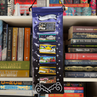 Book-themed decorative banner designed to display LitPins&Co and Felfiramoondesigns's Build Your Own Bookstack series, held against a bookshelf background