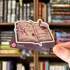 Book shaped sticker inspired by the classics genre, featuring a Jane Austen quote, a quill and ink, and some flowers.
