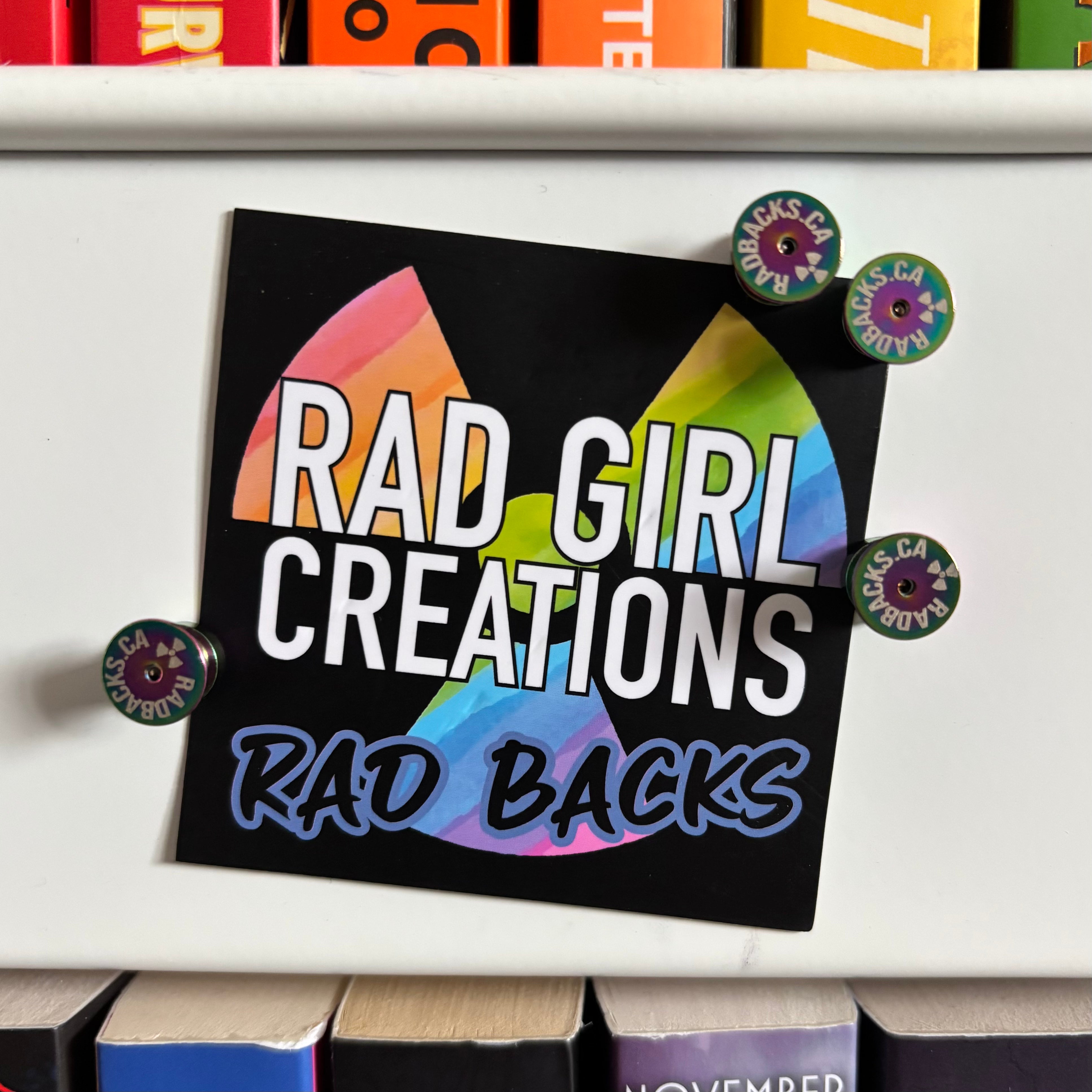 A sign reading "Rad Girl Creations Rad Backs", magnetically held up by four Rad Backs