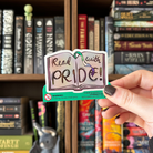 Book-shaped sticker with the text "Read with pride" decorated in colours of various pride flags