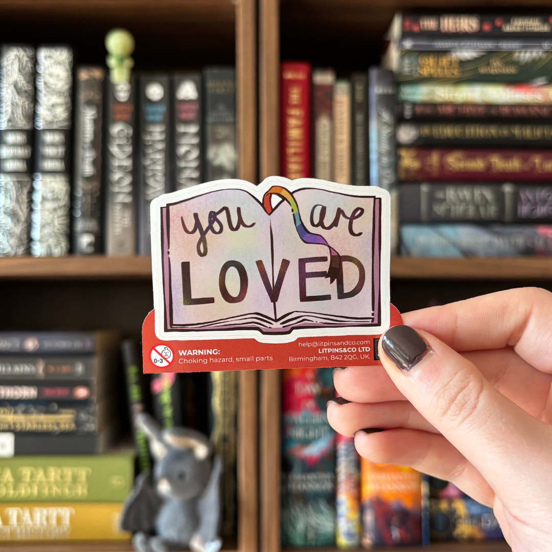 Book-shaped sticker with the text "you are LOVED" decorated in colours of various pride flags