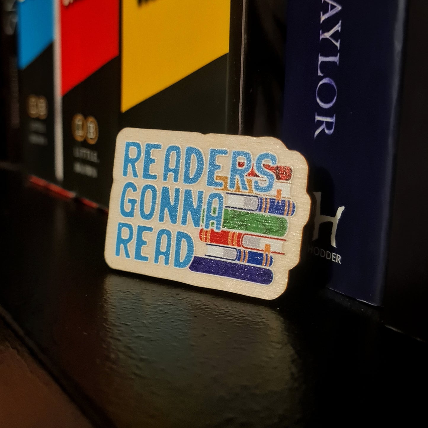 Readers Gonna Read Wooden Pin Badge for Bookworms, featuring a stack of books. 