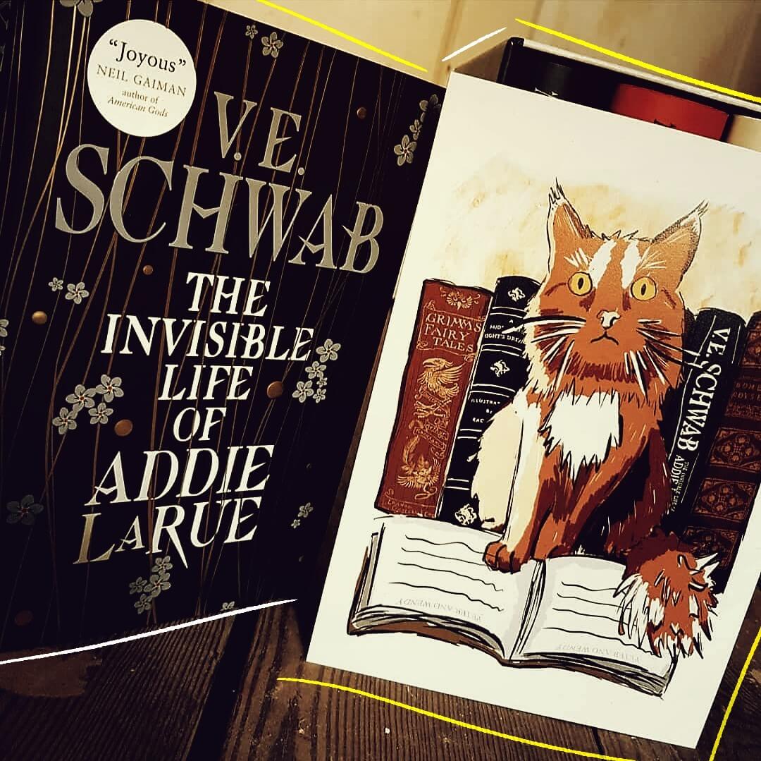 The Invisible Life of Addie LaRue by V.E Schwab hardback standing beside a print of Book the Cat